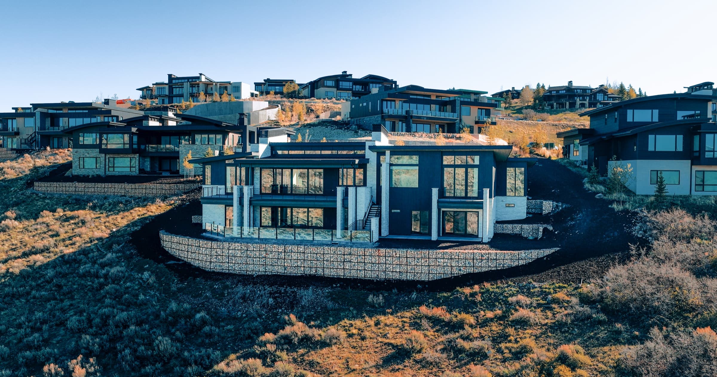 Aerial view of a modern luxury home on a Park City hillside at golden hour