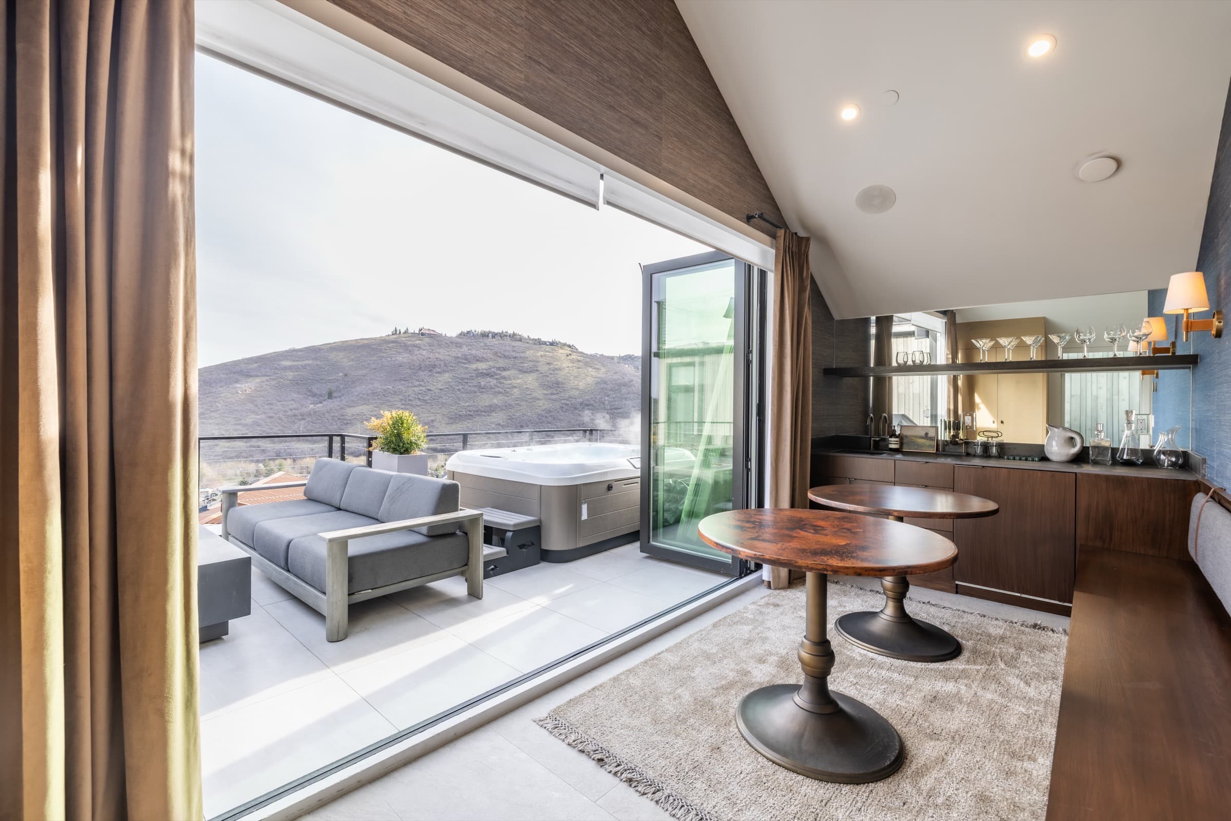 Park City home with sliding glass doors open to a hot-tub patio and mountain view