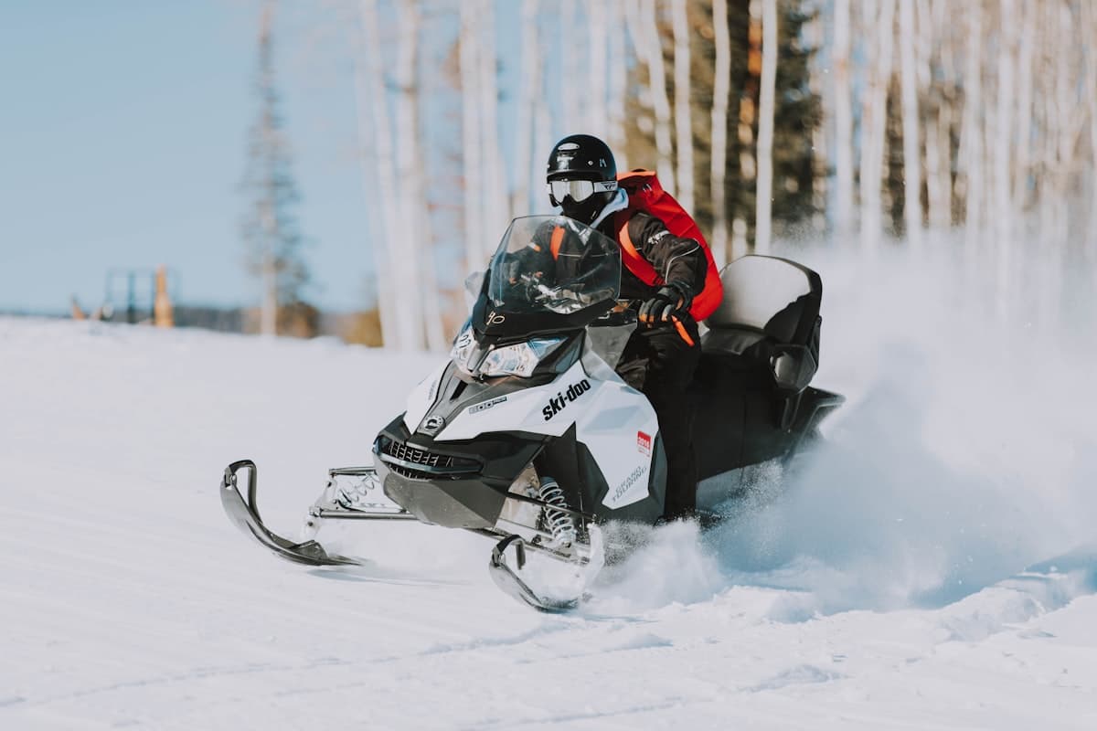Snowmobile rider speeding through snowy aspen terrain